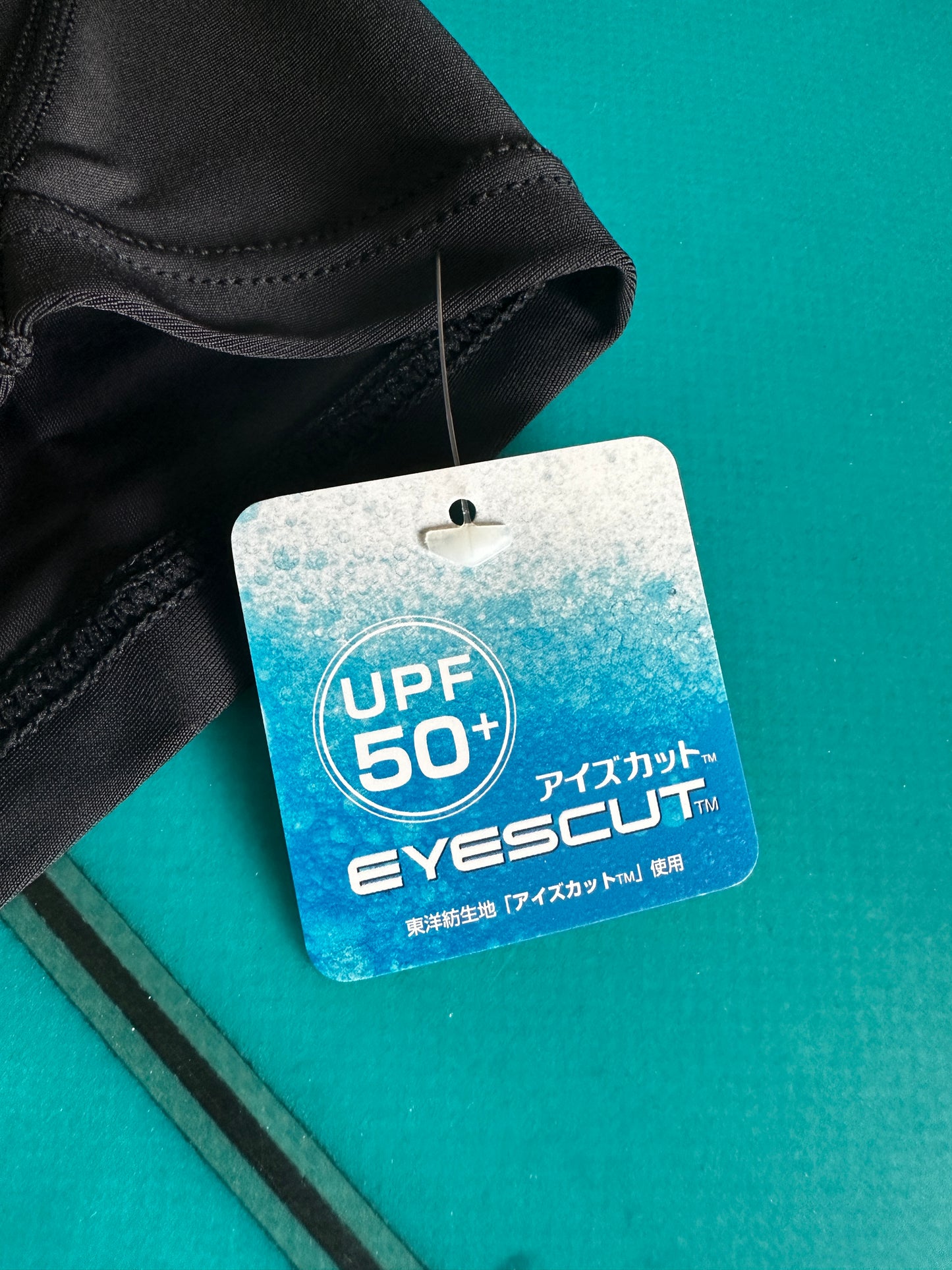 Close-up of UPF50+ UV protection tag on AXXE Classic hooded rashguard.